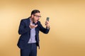 Shocked frustrated young male professional manager dressed in elegant suit looking at mobile phone and gesturing. Business manager