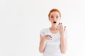 Shocked ginger woman in t-shirt holding smartphone