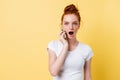 Shocked ginger woman in white t-shirt talking by the smartphone