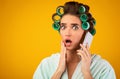 Shocked Girl With Curlers Talking On Cellphone Standing, Yellow Background