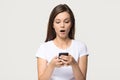 Shocked girl holding phone feeling stunned about unexpected mobile message Royalty Free Stock Photo