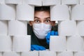 Shocked guy hidind from coronavirus infection among toilet paper rolls