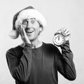 Shocked handsome man in Santa hat. Man with alarm clock. It`s almost twelve o`clock. Christmas time, sales and discounts Royalty Free Stock Photo