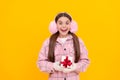 shocked happy kid in winter earmuffs with box. teen girl in mittens hold present Royalty Free Stock Photo