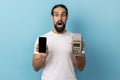 Shocked happy man holding pos terminal and mobile phone with empty display for advertisement. Royalty Free Stock Photo