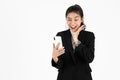 Shocked happy young Asian business woman in suit looking at mobile smart phone over white isolated background Royalty Free Stock Photo