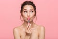 Shocked happy young woman posing isolated over pink wall background holding lipstick Royalty Free Stock Photo