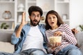 Shocked hindu couple sitting on couch at home, watching triller Royalty Free Stock Photo