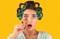 Shocked Housewife Holding Eyelashes Curler Posing In Studio, Yellow Background Royalty Free Stock Photo