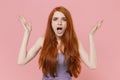 Shocked irritated young redhead woman girl in plaid dress posing on pastel pink background studio portrait