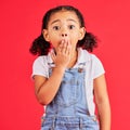 Shocked kid, portrait and hand on mouth in secret, oops and mistake facial expression on isolated red background. Child