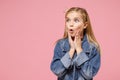 Shocked little blonde kid girl 12-13 years old wearing denim jacket, crown isolated on pastel pink background children Royalty Free Stock Photo