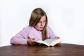 Shocked little girl with a book on a white background