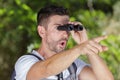 shocked man with binoculars pointing into distance