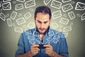 Shocked man busy sending messages emails from smart phone email icons flying of mobile phone Royalty Free Stock Photo