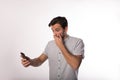 Shocked man covers his mouth with his hand while reading bad news in sms on cell telephone