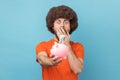 Shocked man holding piggy bank with dollar banknote in hands, being surprised of savings. Royalty Free Stock Photo