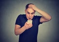 Shocked man looking at his mobile phone seeing bad news reading text message Royalty Free Stock Photo