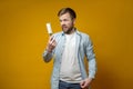 Shocked man looking at roll with duct tape, which had just cleaned his clothes from animal hair, on a yellow background. Royalty Free Stock Photo