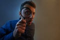 Shocked man with magnifying glass on grey background. Curious young man with magnifying glass Isolated on grey background