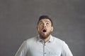 Shocked man with opened mouth widely looking overhead closeup portrait