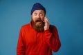 Shocked man shouting while talking on mobile phone isolated over blue wall Royalty Free Stock Photo