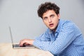 Shocked man sitting at the table with laptop