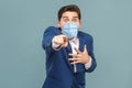 Shocked man with surgical medical mask pointing finger at camera with shocked face Royalty Free Stock Photo