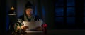 Shocked man in winter clothes looks at household expenses bills while sitting in candlelight in cold room. energy crisis, heating