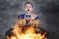 Shocked messy man with apron holding pan in fire burning the food in kitchen disaster and unskilled and unexperienced terrible ho Royalty Free Stock Photo