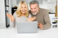 Shocked middle-aged couple staring at the laptop screen, surprised with unexpected news Royalty Free Stock Photo