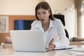 Shocked millennial freelance employee girl looking at laptop