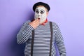 Shocked mime artist standing in disbelief closing his mouth with a palm