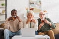 Shocked multiethnic friends holding cups near