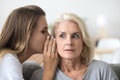 Shocked older woman listening to young friend whispering secret