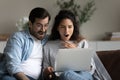Shocked overjoyed young couple looking on laptop, reading amazing news