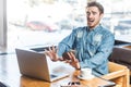 Shocked panicked scared man working on laptop showing stop gesture to computer screen looks frighten