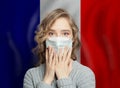 Shocked panicking woman in medical face mask with France background