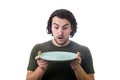 Shocked person holding an empty dish plate in his hands, looking astonished isolated on white background. People has no food to