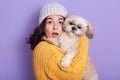 Shocked pretty younggirl holding dog and looking directly at camera with opened mouth, attractive female expressing astonishment Royalty Free Stock Photo