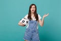 Shocked puzzled perplexed young woman football fan support favorite team with soccer ball spreading hand isolated on