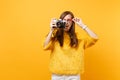 Shocked puzzled young woman holding heart glasses and taking pictures on retro vintage photo camera isolated on bright