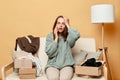 Shocked sad unhappy woman sitting on sofa opening carton box talking on mobile phone checking her order talking to assistant has