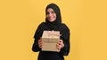 Shocked Saudi woman in black hijab open craft wrapped gift box with desired present isolated orange