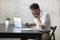 Shocked businessman after reading bad news in laptop about his business sits at the desk with documents Royalty Free Stock Photo