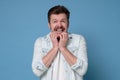 Shocked scared caucasian man with mustache biting nails in panic Royalty Free Stock Photo