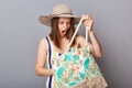 Shocked scared woman wearing striped one-piece swimsuit and straw wide brim hat posing isolated on gray background looking at her Royalty Free Stock Photo