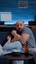 Shocked scared young couple eating popcorn watching horror movie on tv Royalty Free Stock Photo