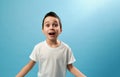 Shocked schoolboy expressing surprise on camera. Facial emotions on blue background