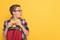 Shocked schoolboy with glasses holding backpack